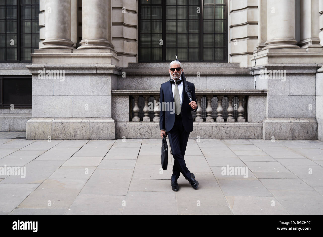 UK, London, Portrait von stilvollen Geschäftsmann mit Sonnenbrille und Regenschirm tragen Anzug und Krawatte Stockfoto