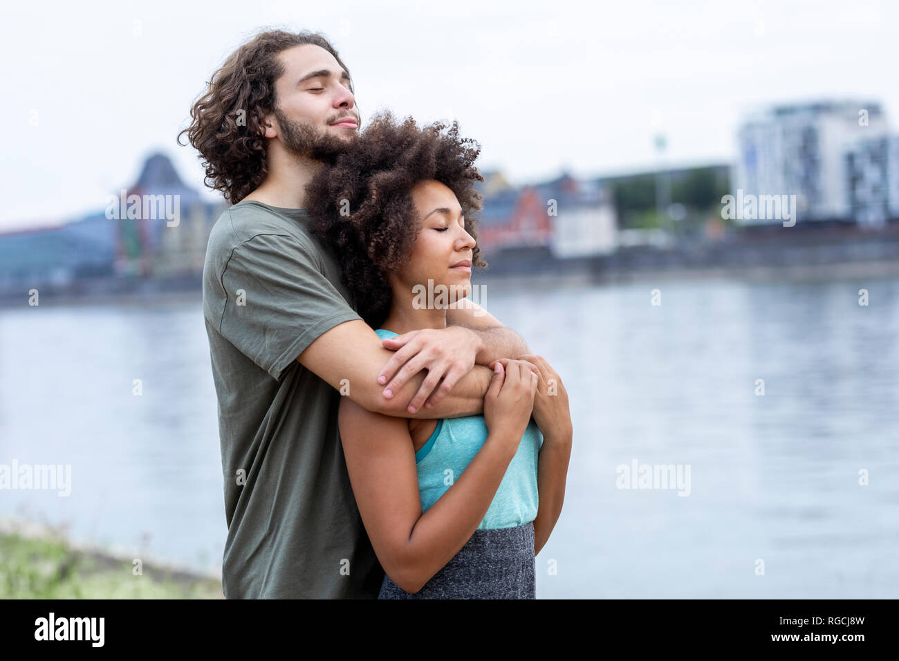 Deutschland, Köln, junges Paar umarmen am Flußufer Stockfoto