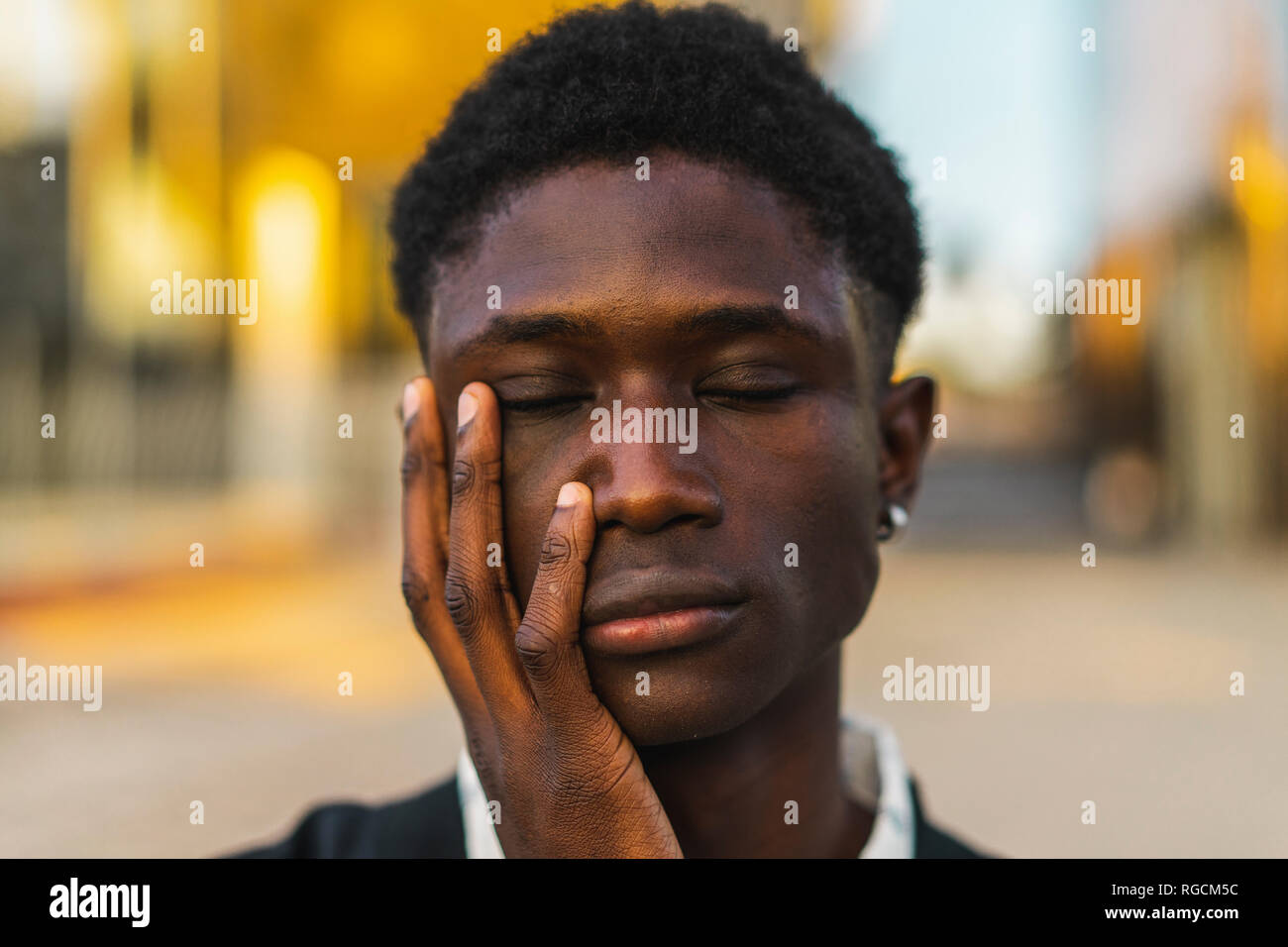 Junge schwarze Mann mit geschlossenen Augen und mit der Hand auf das Gesicht Stockfoto