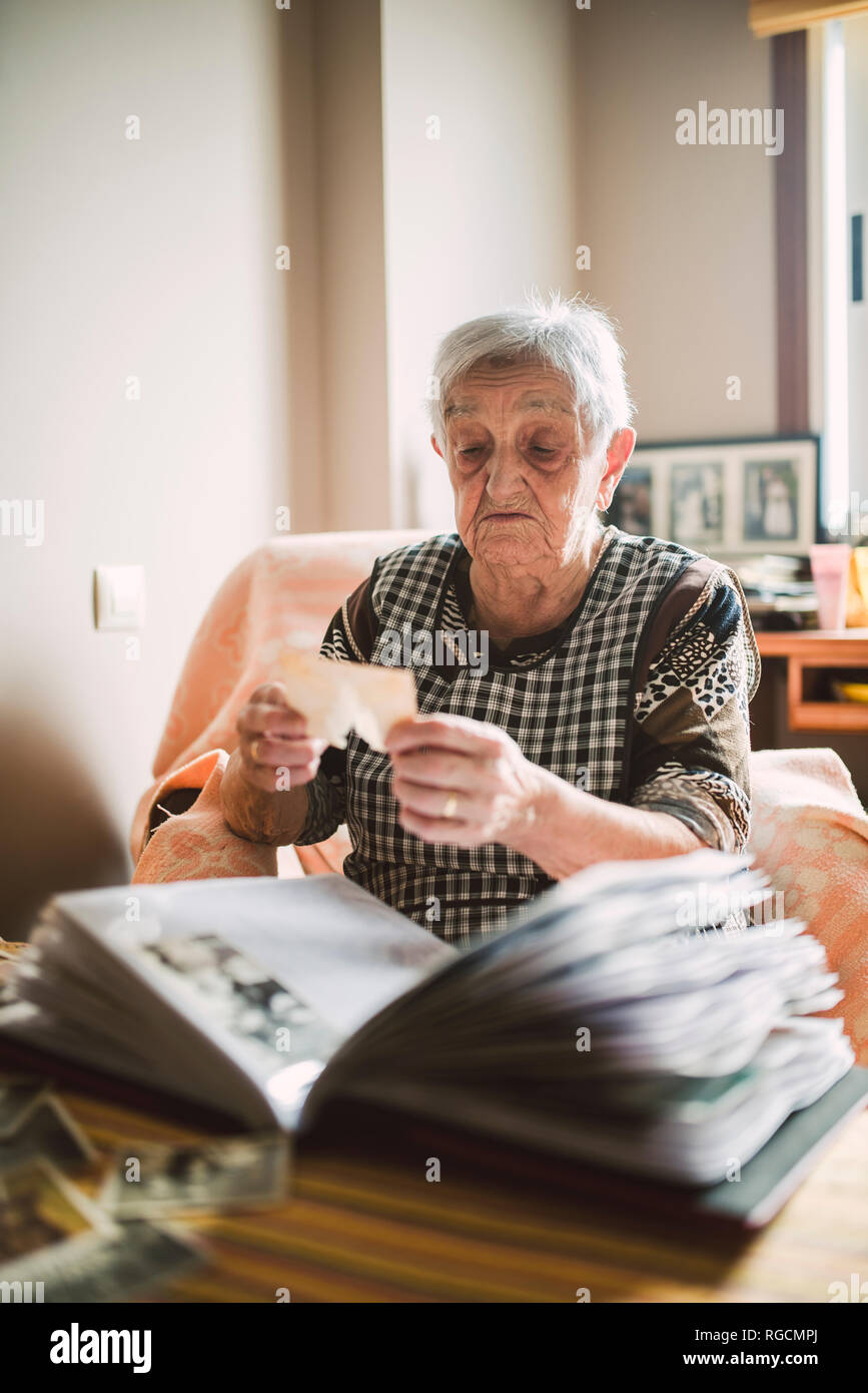 Ältere Frau an Foto betrachten, bevor sie in ein Fotoalbum Stockfoto