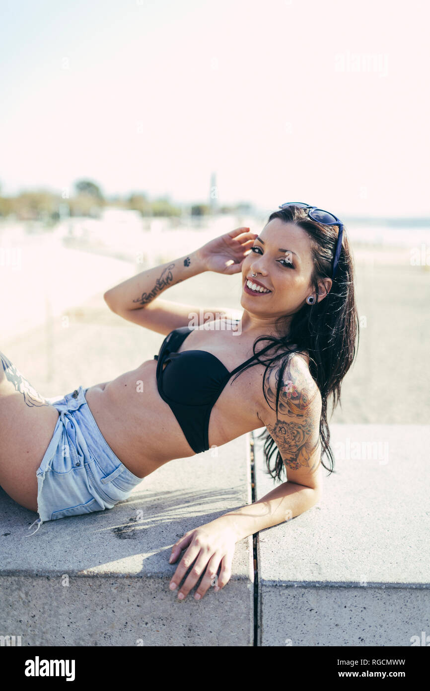 Porträt der jungen Frau mit Nasen Piercing und Tattoos entspannen im Sonnenlicht Stockfoto
