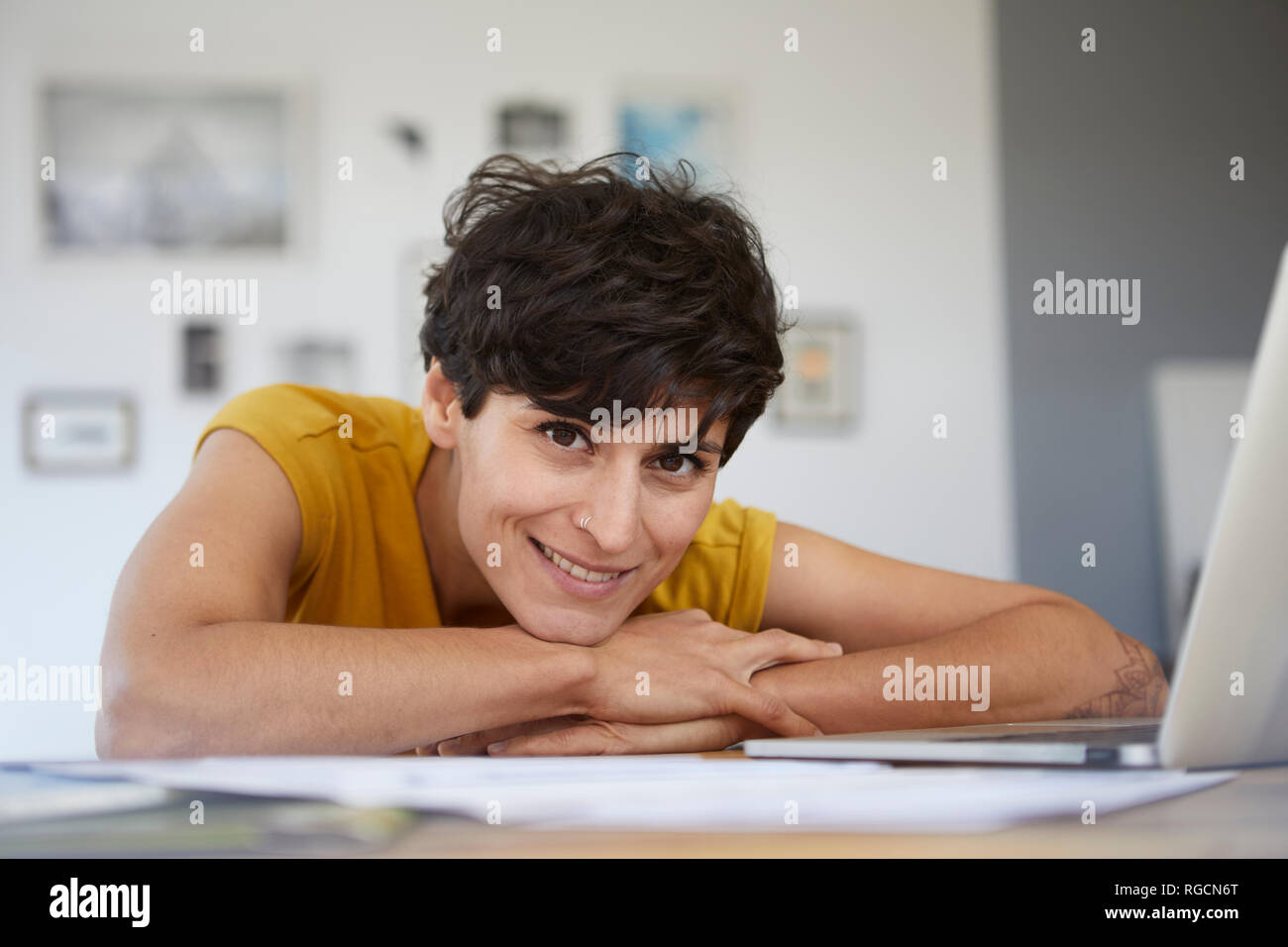 Porträt der lächelnde Frau zu Hause lehnte sich auf Tabelle Stockfoto