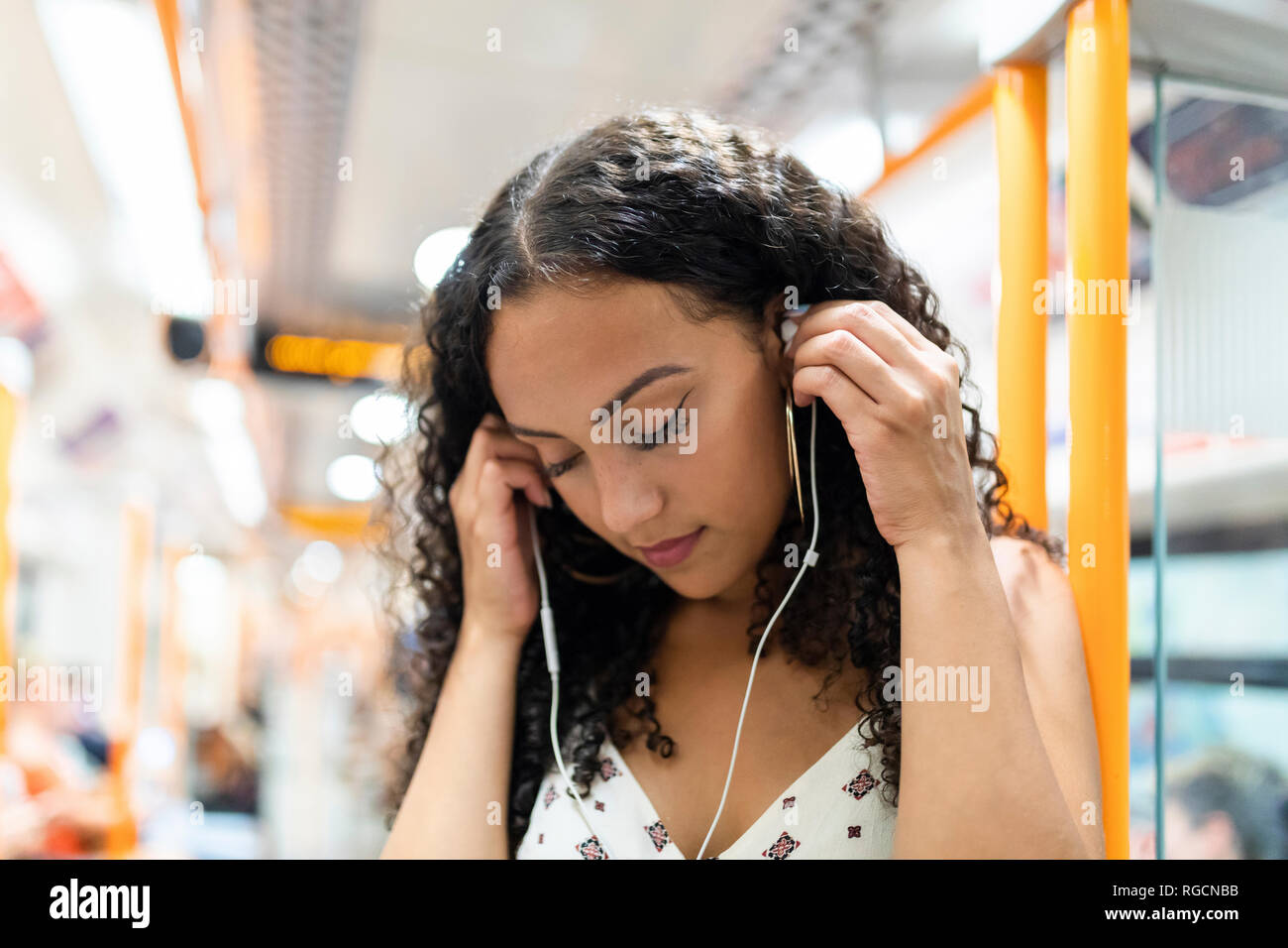 Junge Frau Musikhören mit Kopfhörern in der U-Bahn Stockfoto