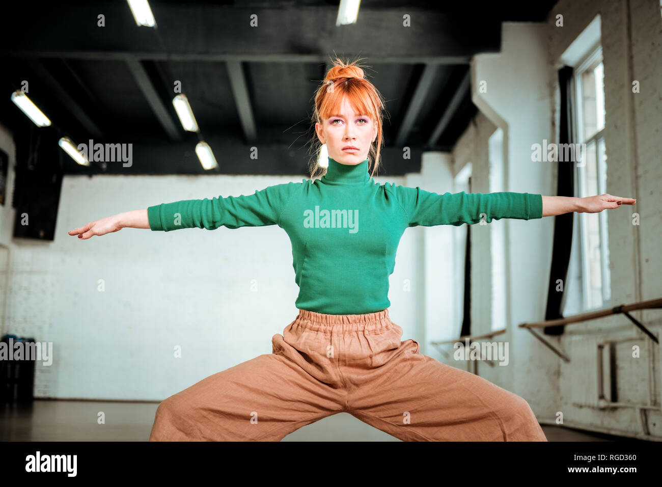 Gut aussehende slim Yoga Trainer in einem grünen Rollkragen Übungen für Beine Stockfoto