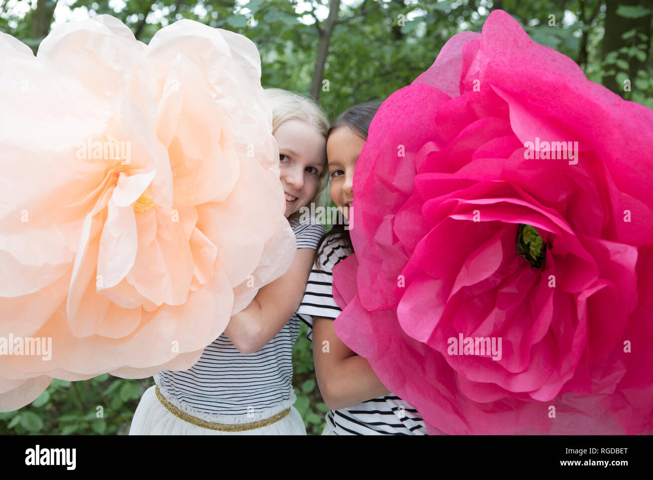 Zwei lächelnde Mädchen mit zwei übergroße Künstliche Blumen Stockfoto