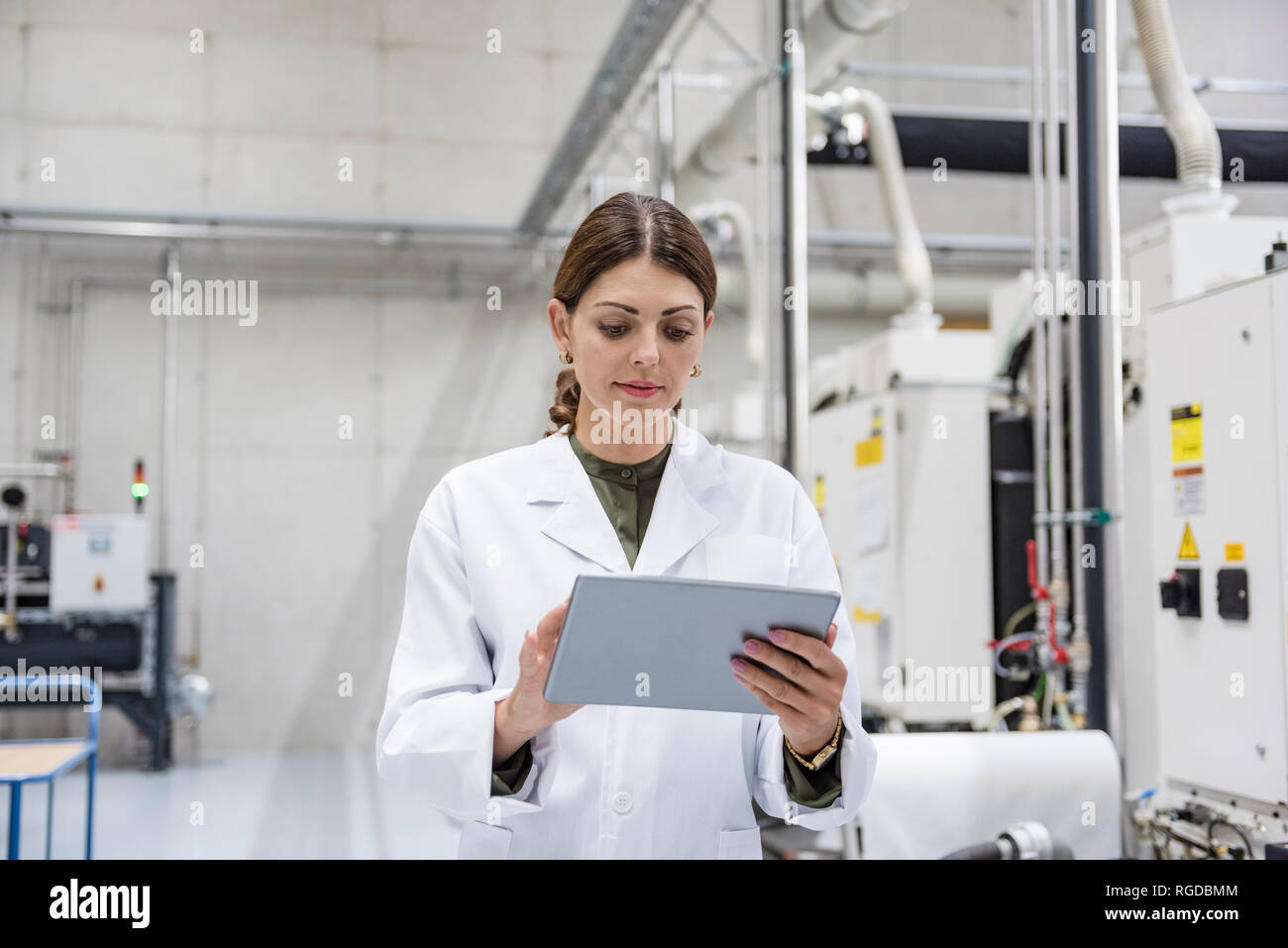 Frau Kontrolle der Fertigung Maschinen in High Tech Unternehmen, indem Sie digitale Tablet Stockfoto