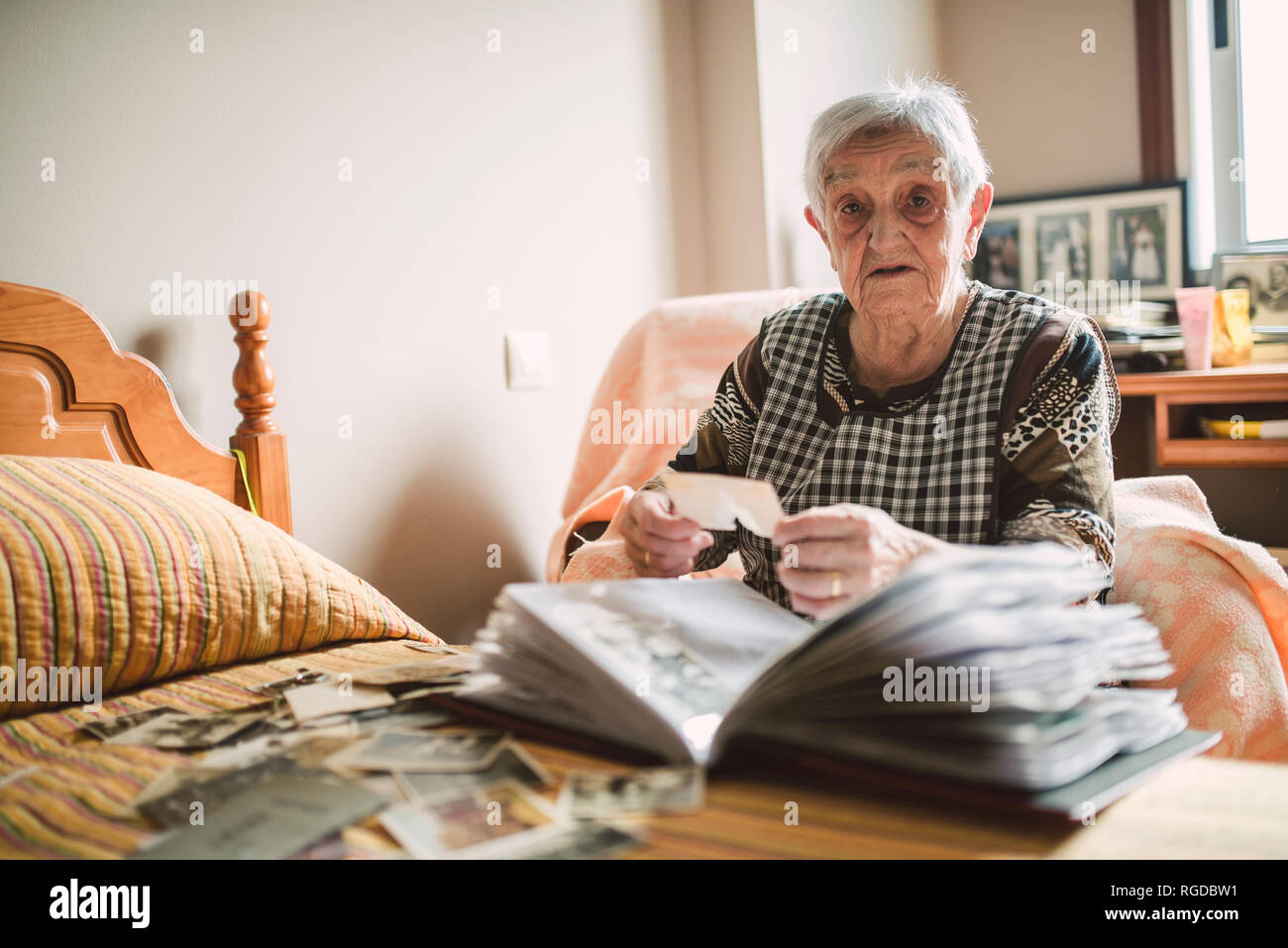 Portrait der älteren Frau Hinzufügen von alten Fotos zu einem Fotoalbum zu Hause Stockfoto