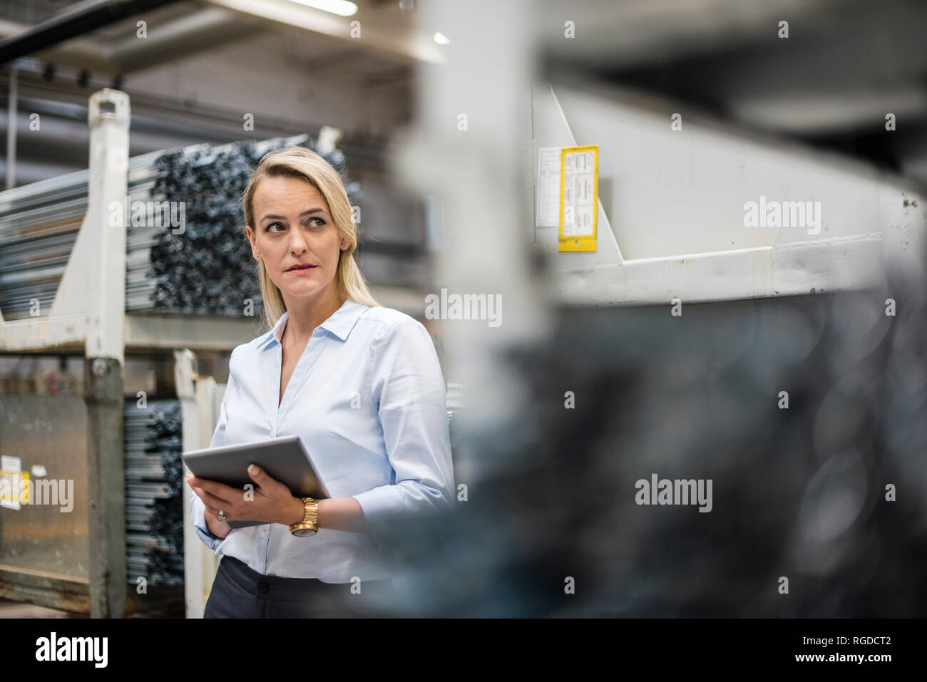 Blonde Frau mit Tablette im Hochregallager Stockfoto