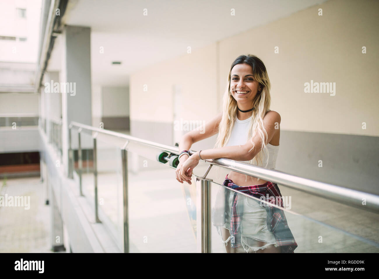 Lächelnde junge Frau lehnte sich auf Geländer, Porträt Stockfoto