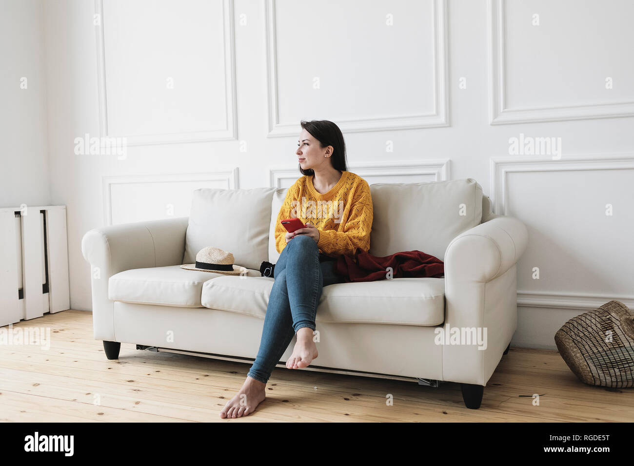 Entspannt junge Frau mit Smartphone sitzen auf der Couch im neuen Zuhause suchen auf Distanz Stockfoto