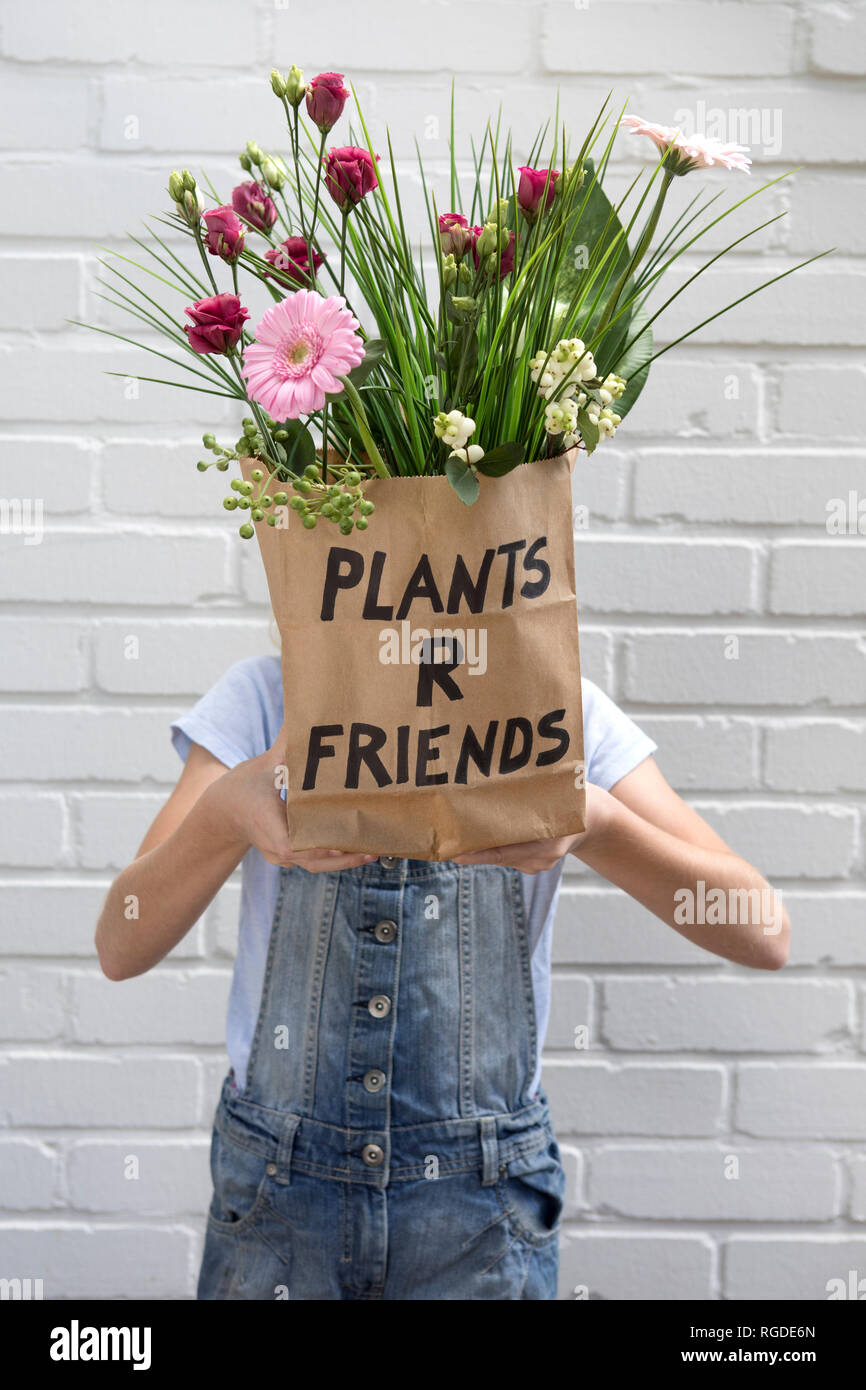 Mädchen verstecken Gesicht hinter Papiertüte mit Blumen Stockfoto