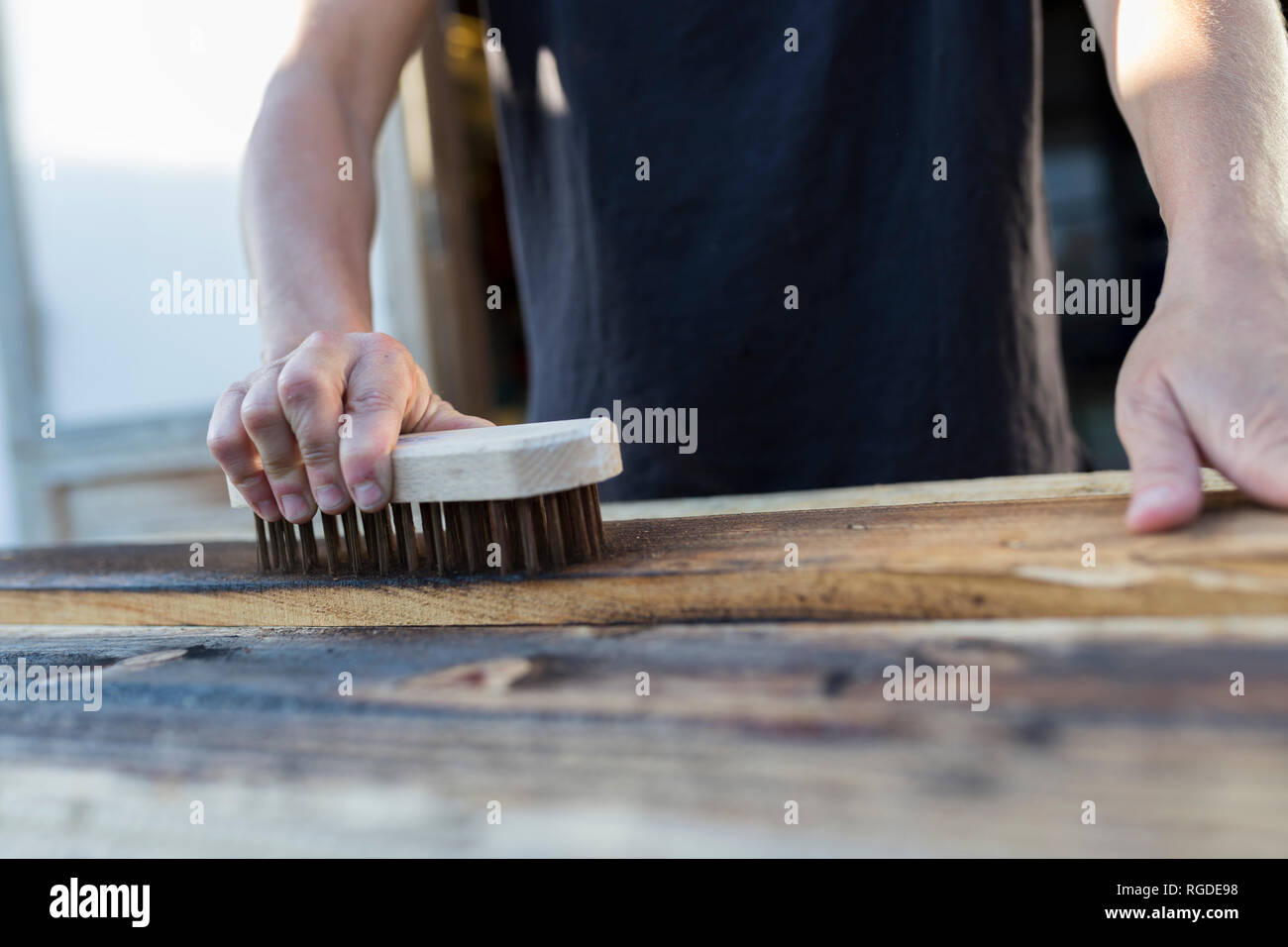 Handwerkerin mit Bürste am Stück Holz Stockfoto