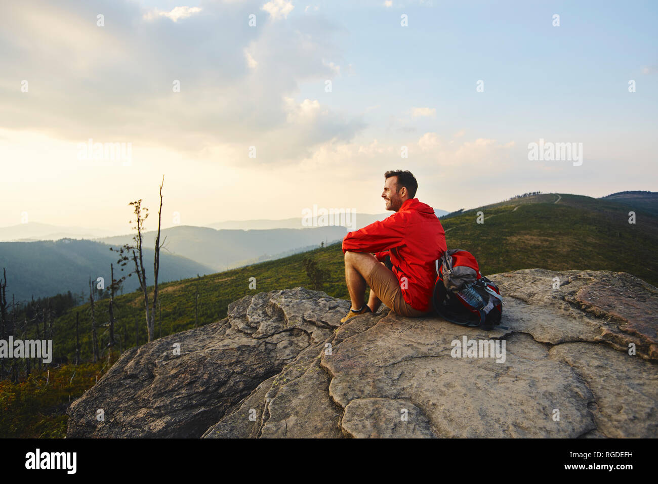 Mann sitzt auf Felsen genießen die Aussicht während der Wanderung Stockfoto