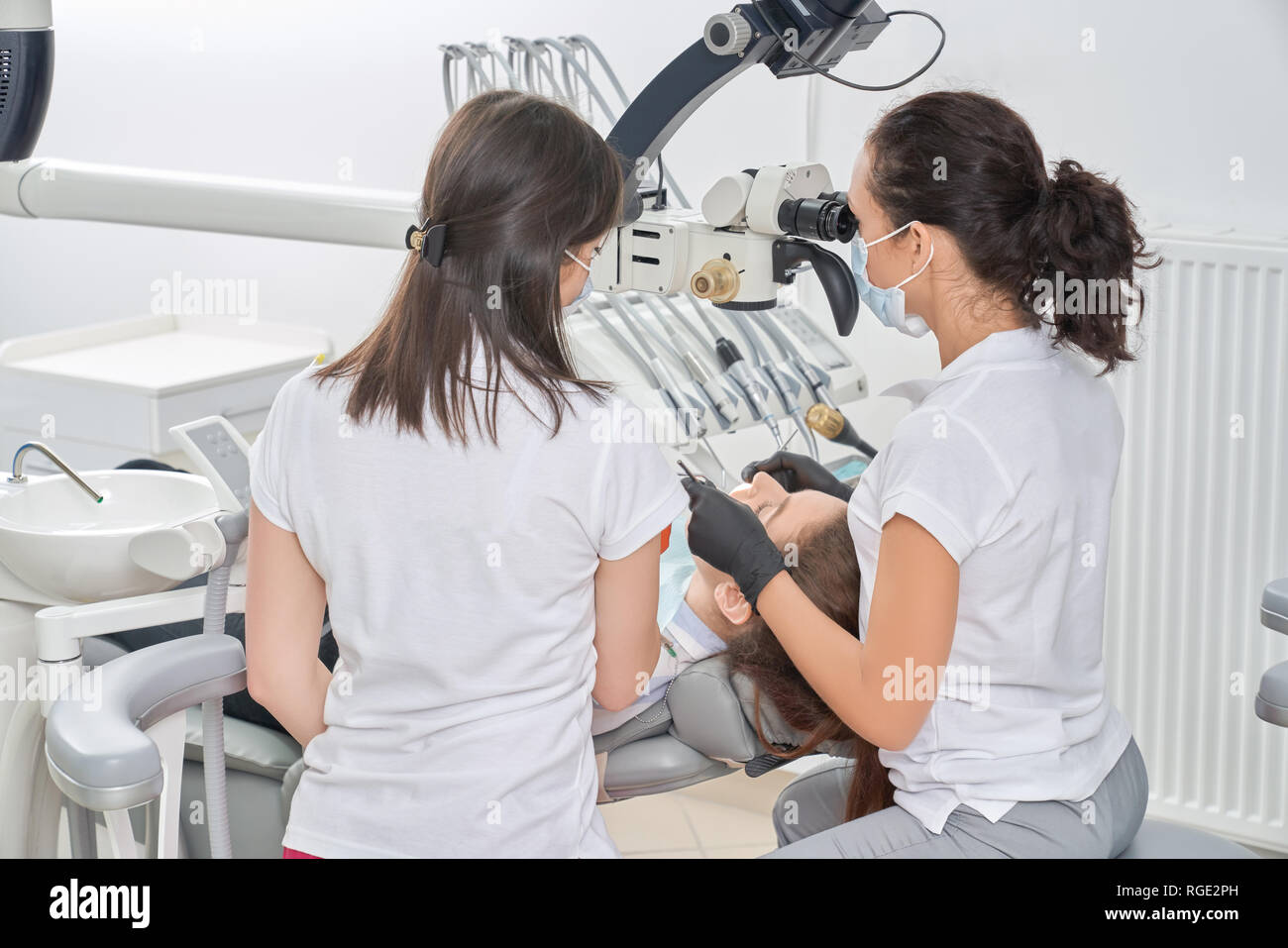 Ansicht von der Rückseite der weiblichen Zahnärzte und Kontrolle der Zähne der weiblichen Patienten in der Zahnarztpraxis. Junge Frau in Klinik und Pflege über Zähne. Konzept der Zahntechnik und Zahnmedizin. Stockfoto