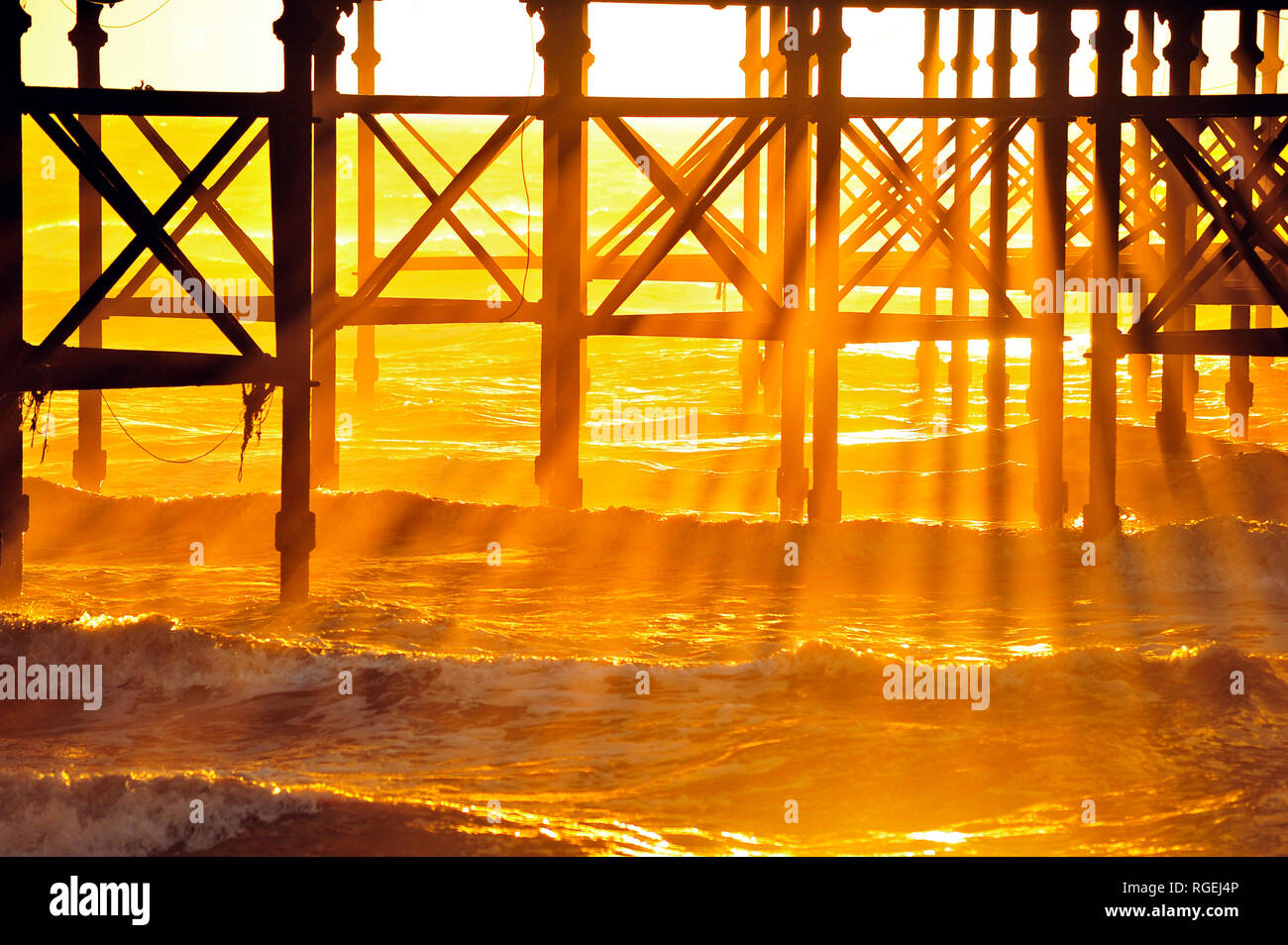 Goldene Wellen von Licht durch das Bügeleisen arbeiten unterhalb South Pier und in den Wellen der Flut Stockfoto
