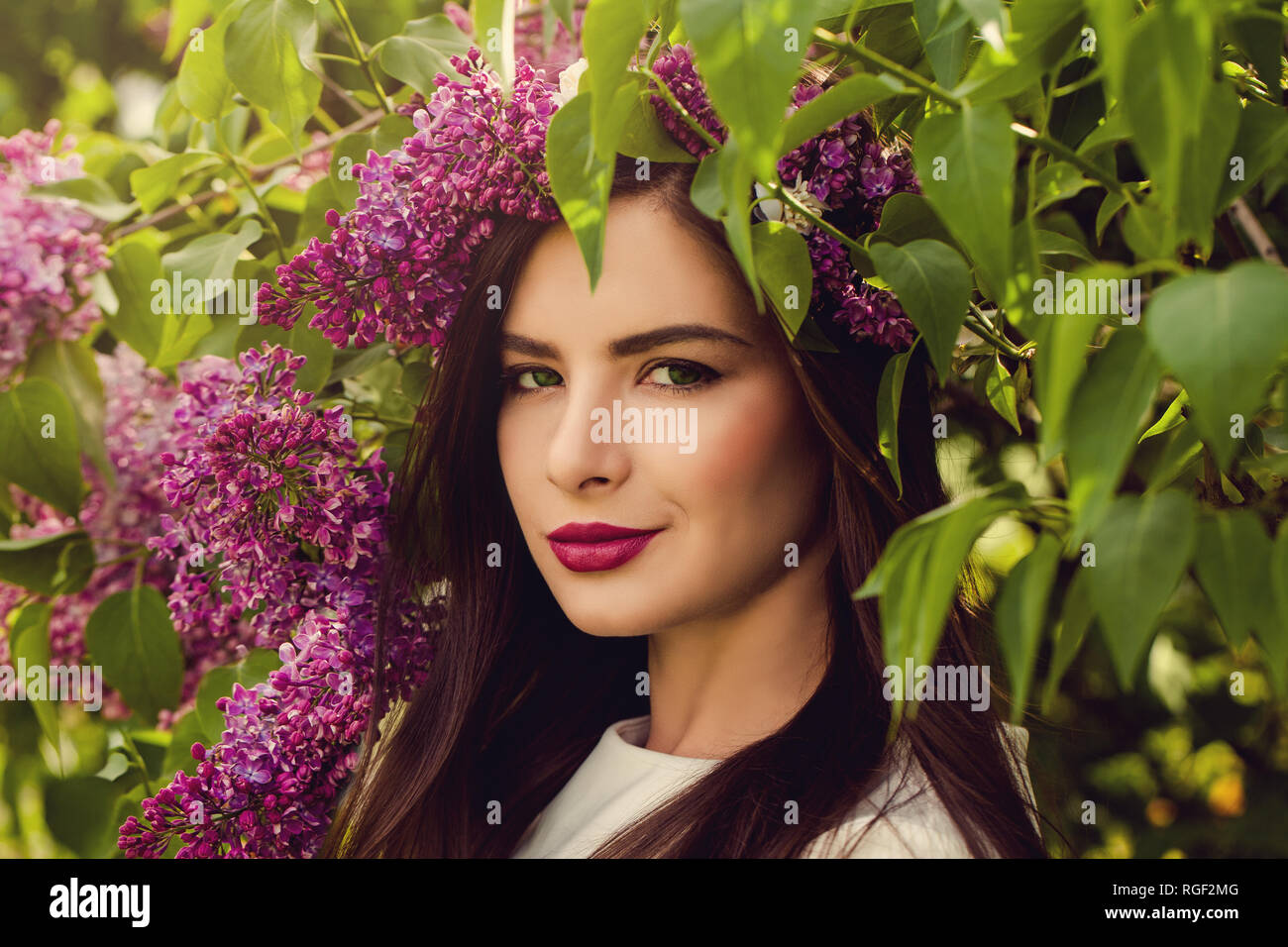 Fröhliche Frau mit Blumen im Freien. Junge perfekte Weibliche Model in der Blüte Garten Stockfoto