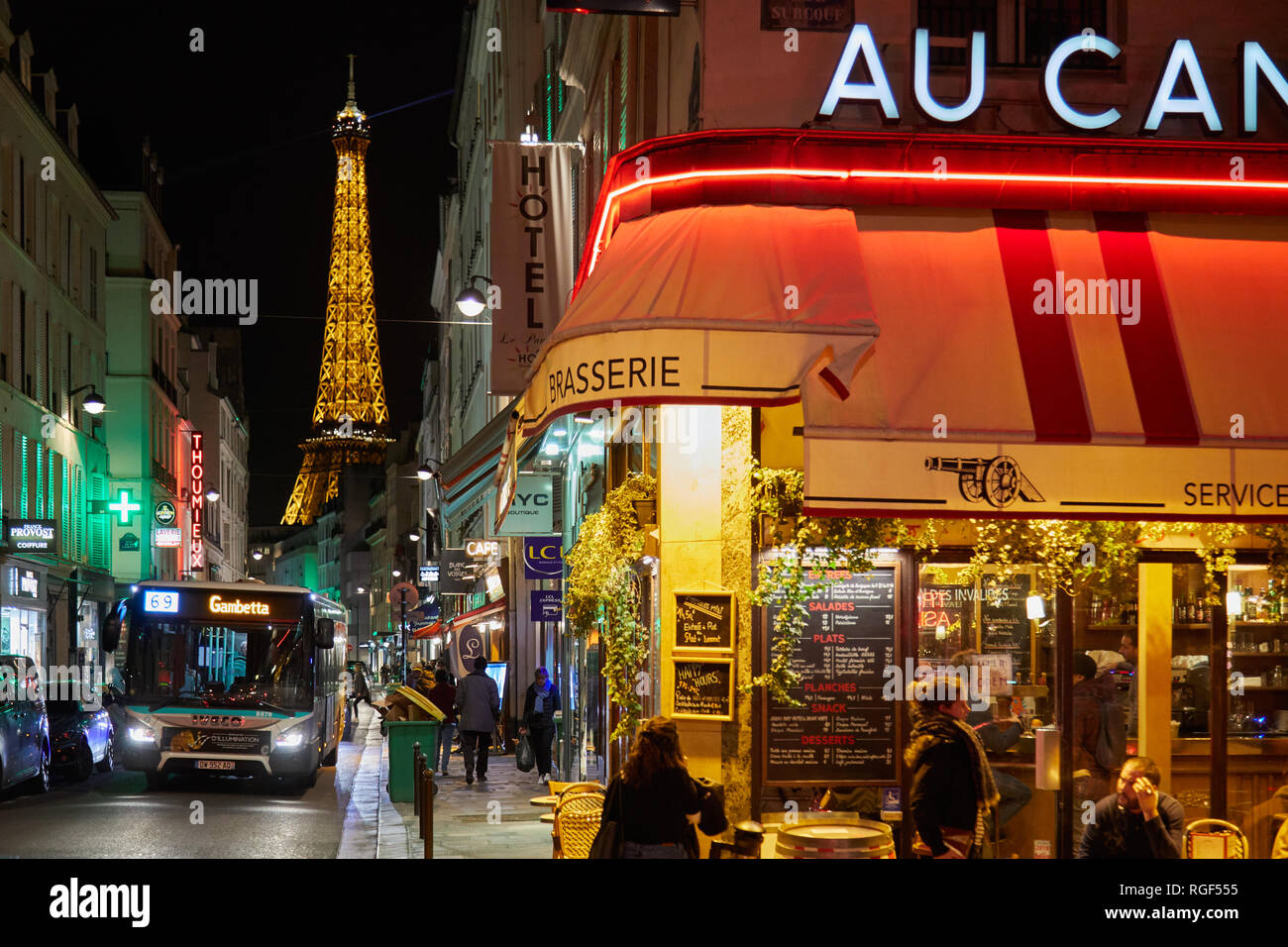 PARIS - 8. NOVEMBER 2018: Eiffelturm bei Nacht und Straße beleuchtet mit Bus, Menschen und typischen Restaurant in Paris, Frankreich Stockfoto