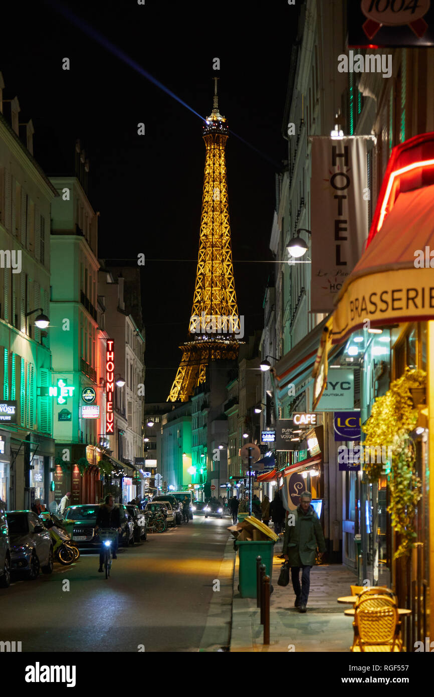 PARIS - 8. NOVEMBER 2018: Eiffelturm bei Nacht und Straße beleuchtet mit Menschen und typischen Restaurant in Paris, Frankreich Stockfoto