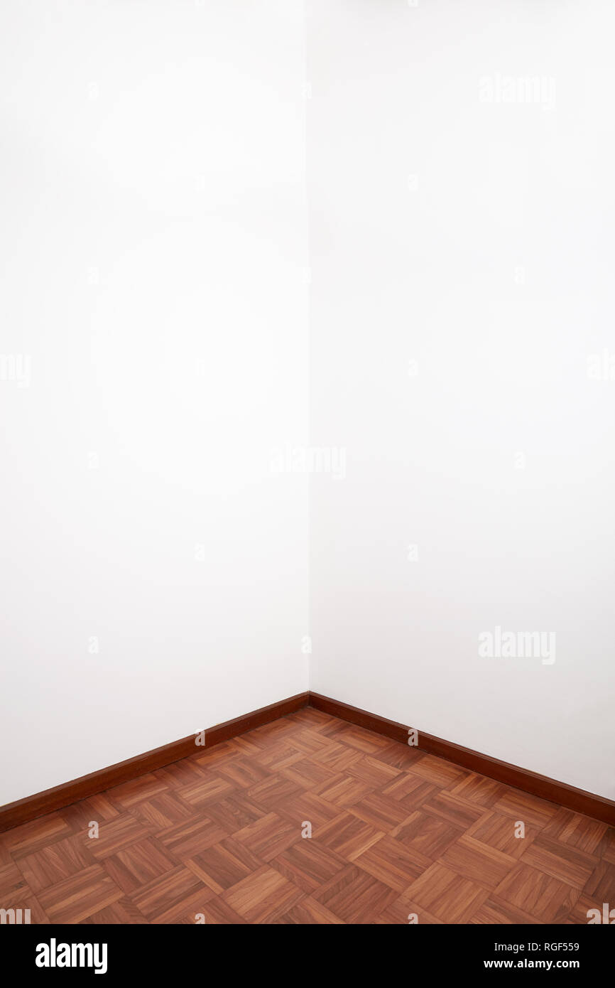 Zimmer Ecke mit braunem Holz Fliesen und weiße leere Wand Stockfoto