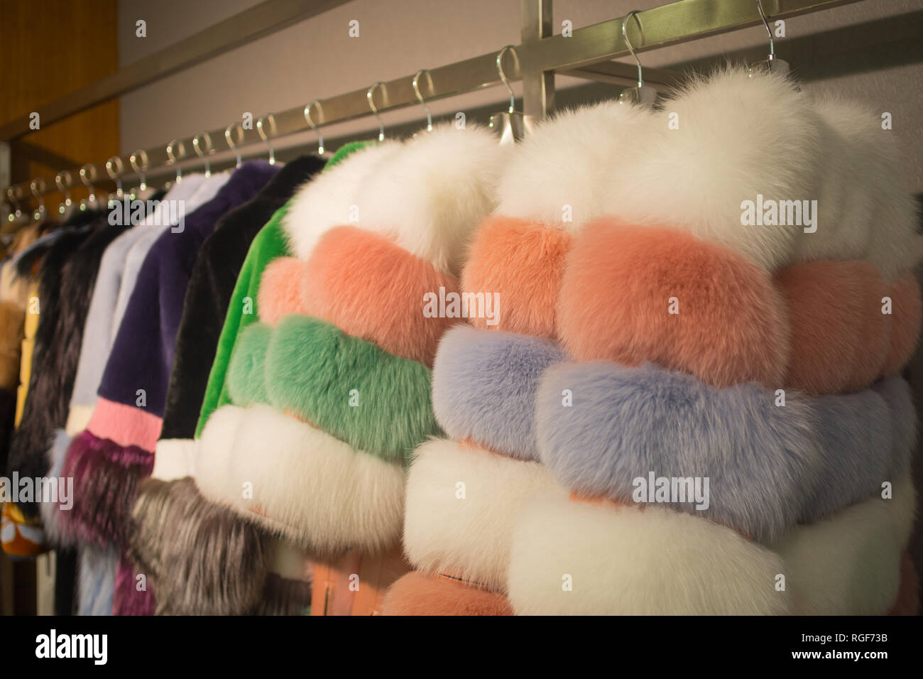 Fancy und bunten weiblichen Pelzmäntel auf Kleiderbügeln im Shop zum Verkauf. Stockfoto