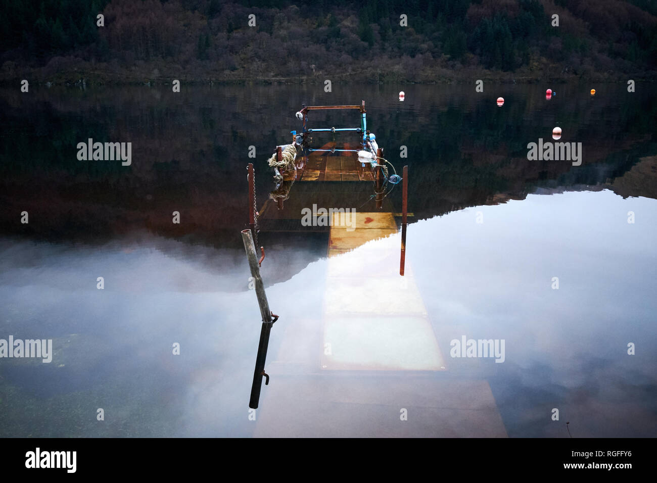 Ein verlassener Steg unter dem Wasser von loch Eck in Argyll mit Bergen reflektiert und eine Verankerung Bojen Stockfoto