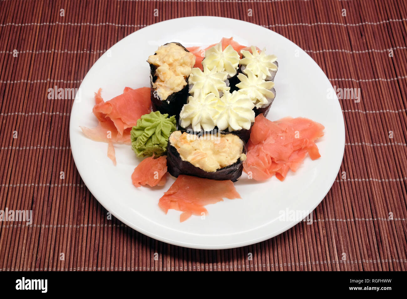 Sushi Stücke auf weiße Platte auf braunen Rattanmöbeln Strohmatte Draufsicht closeup Stockfoto