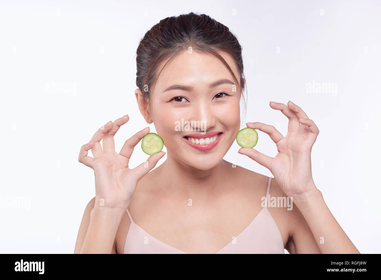 Junge asiatische Frau mit Gurke in Scheiben schneiden, in ihre Hände auf weißem Hintergrund Stockfoto
