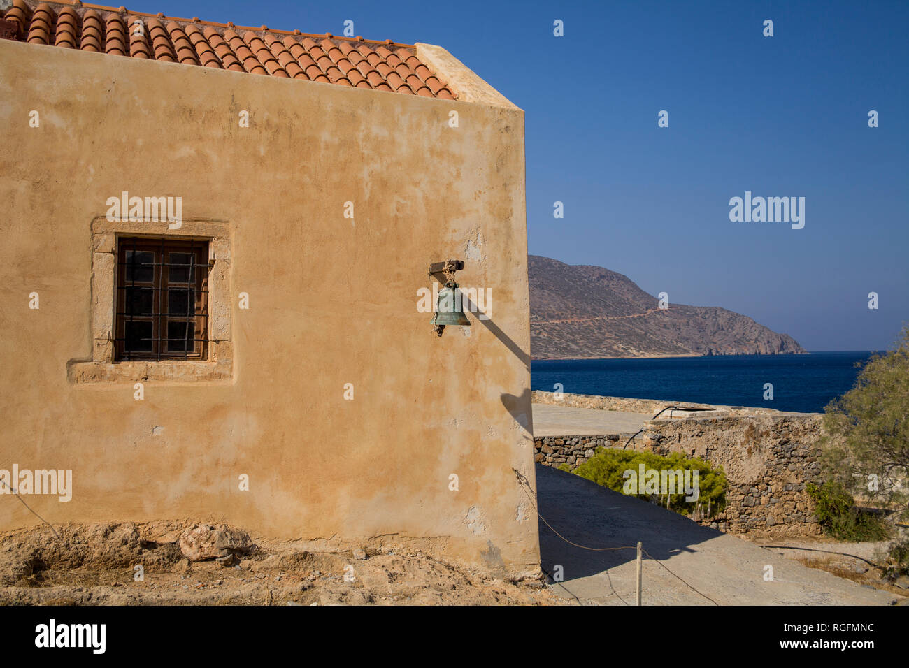 Ein Fragment der Kirchenmauer in der Festung Spinalonga. Eine Klingel an der Wand eines kleinen Kapelle. Stockfoto