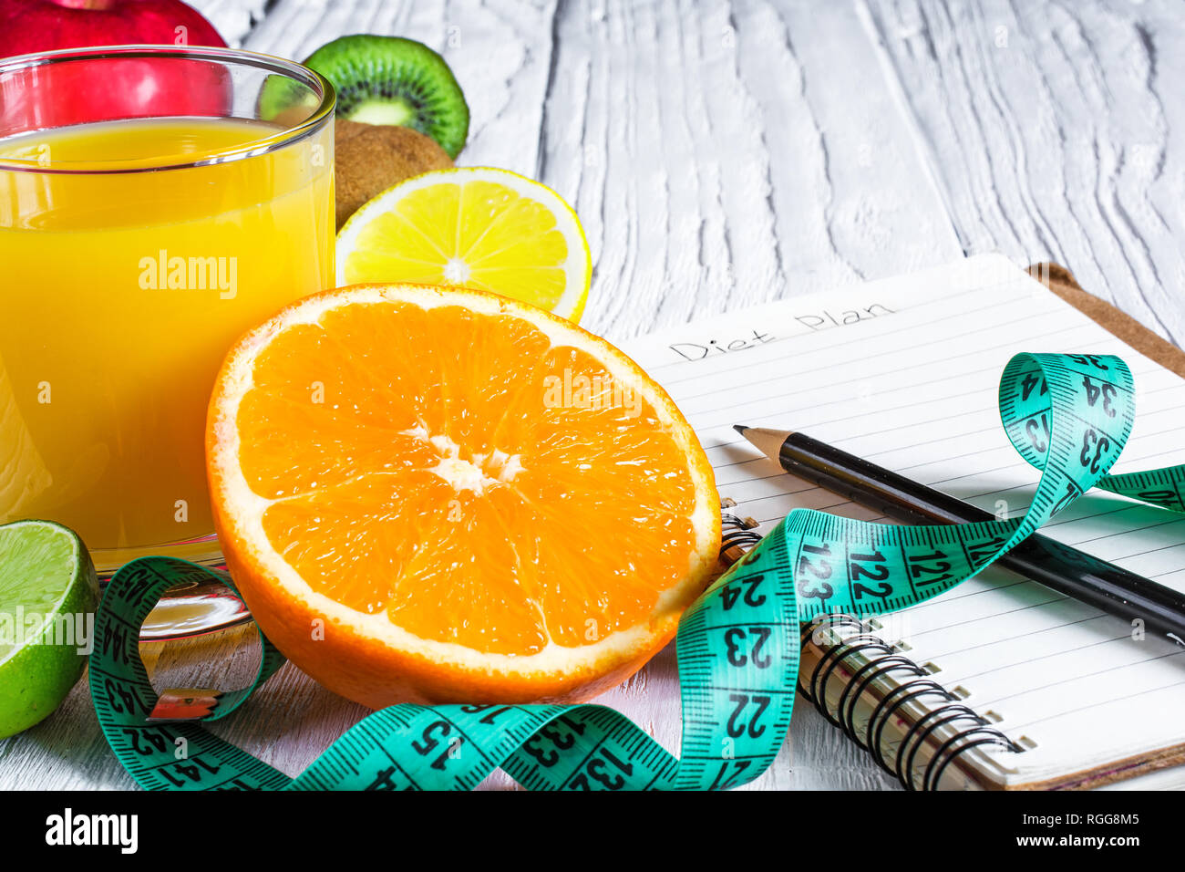 Fitness Concept mit Früchten und frischen Saft. Fitness Motivation mit Zentimeter- und Notebook auf weißem Holz- Hintergrund. Nach oben Schließen Stockfoto