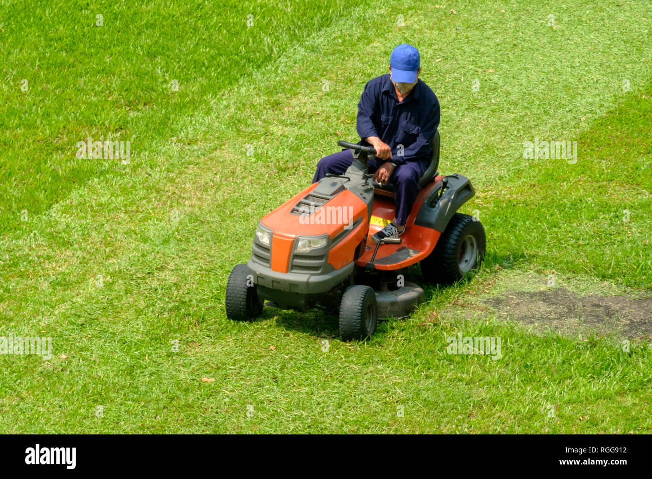 Hohe Betrachtungswinkel und einer Person, die den Rasen zu mähen und schneiden das Gras mit einem großen motorisierten Rasenmäher Stockfoto