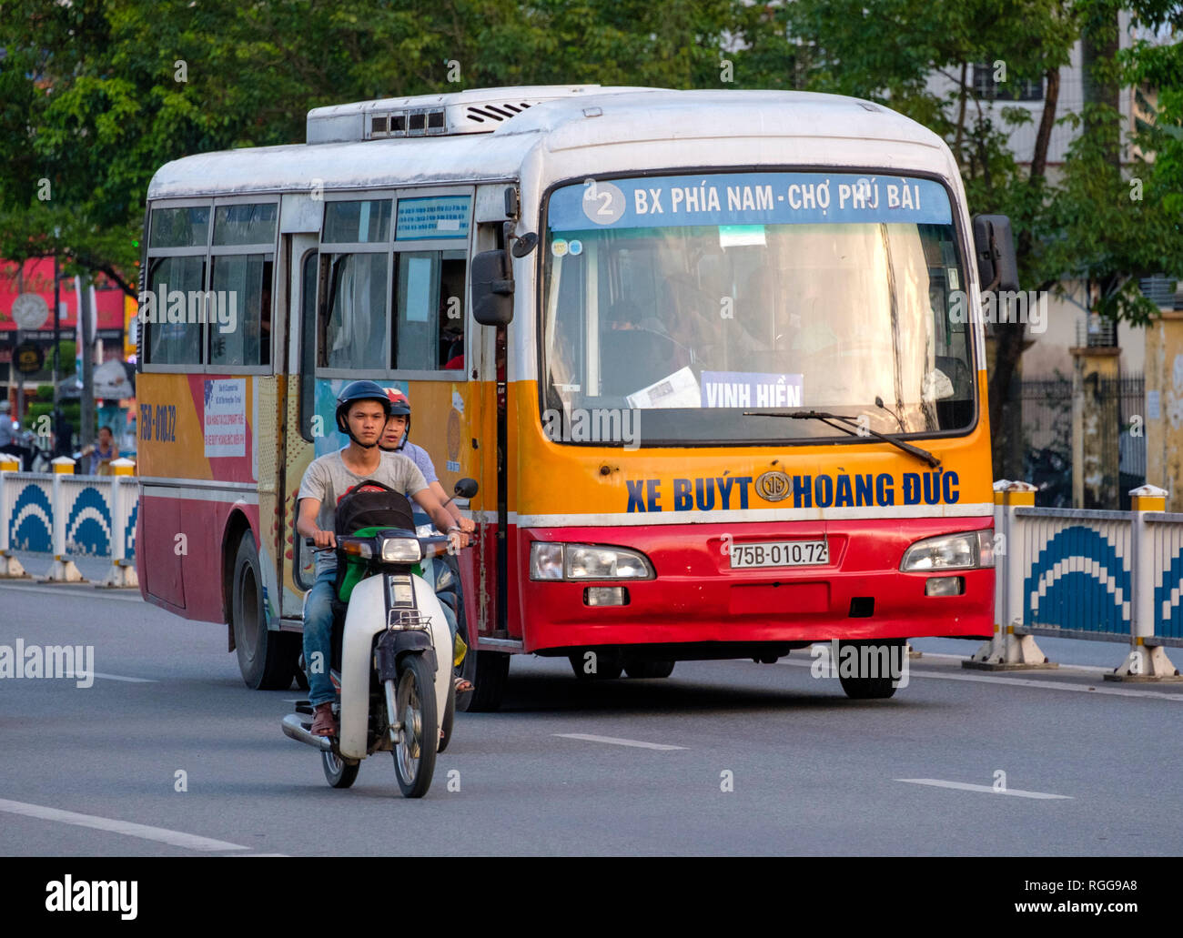 Öffentliche Verkehrsmittel Bus und Motorrad mit zwei Personen teilen sich die Straße in Hue, Vietnam, Südostasien Stockfoto