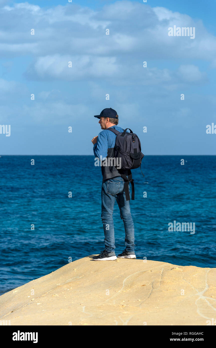 Mann mit einem Rucksack stehen am Rand eines Kalkstein mit Meerblick Stockfoto