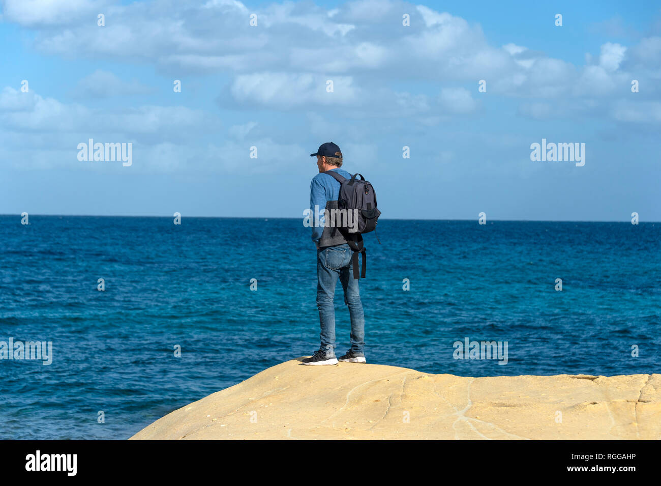 Mann mit einem Rucksack stehen am Rand eines Kalkstein mit Meerblick Stockfoto