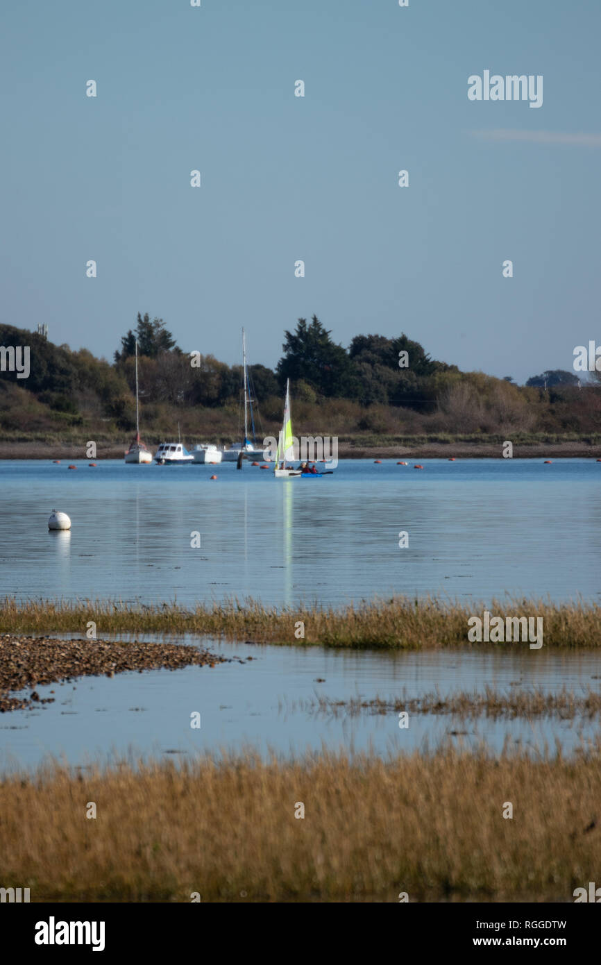 Ruhiges Wasser in einem englischen Hafen mit Segelbooten im Hintergrund Stockfoto