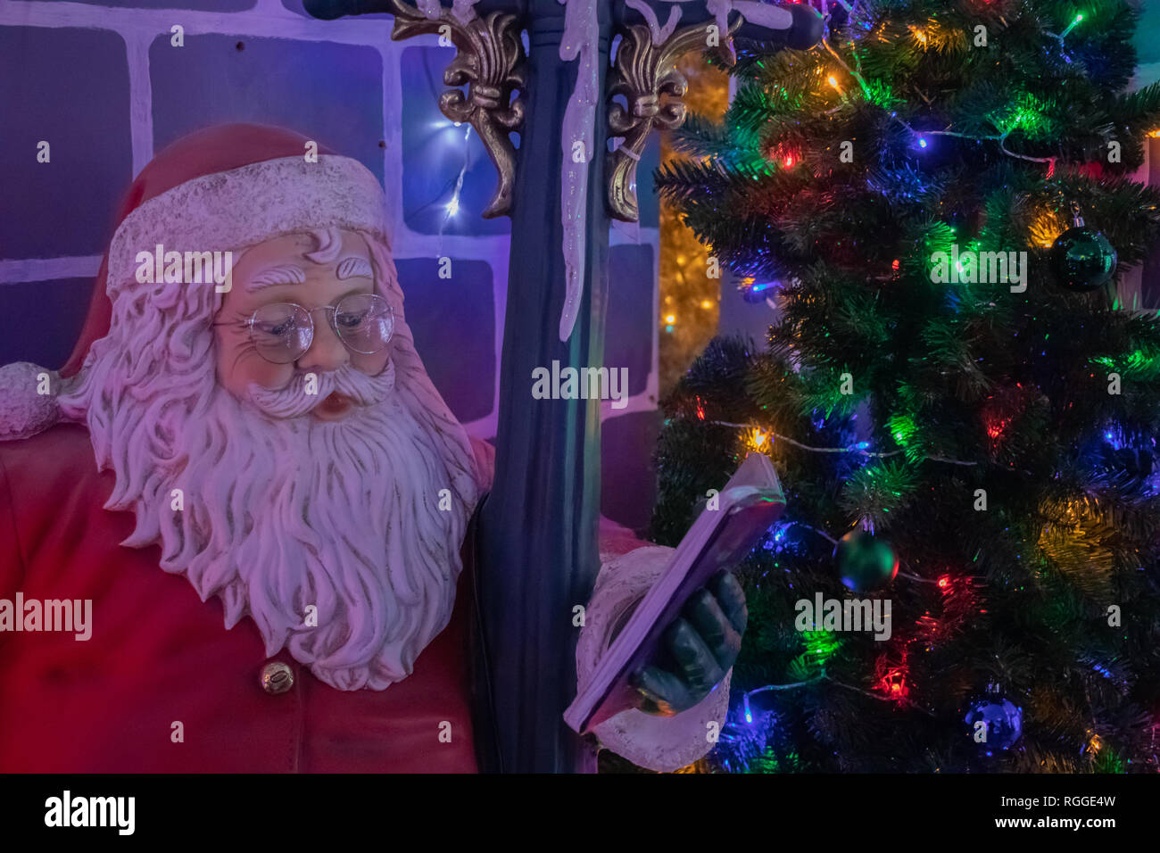 Vater Weihnachten Dekoration stand neben einem Weihnachtsbaum mit Weihnachtsbeleuchtung auf Stockfoto