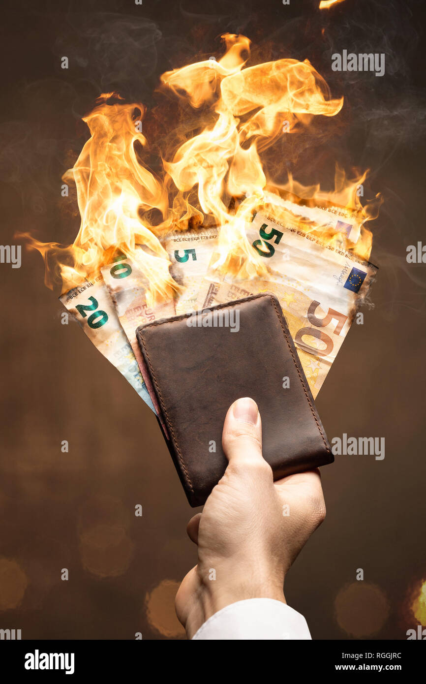 Brennende Euro Rechnungen in einem in der Hand gehaltenen Wallet Stockfoto