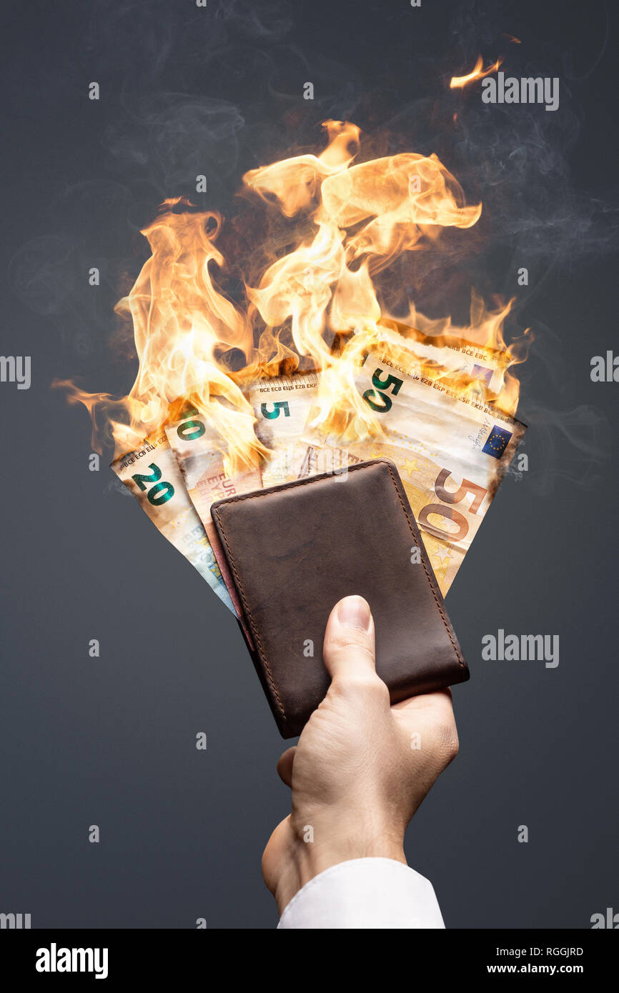 Brennende Euro Rechnungen in einem in der Hand gehaltenen Wallet Stockfoto