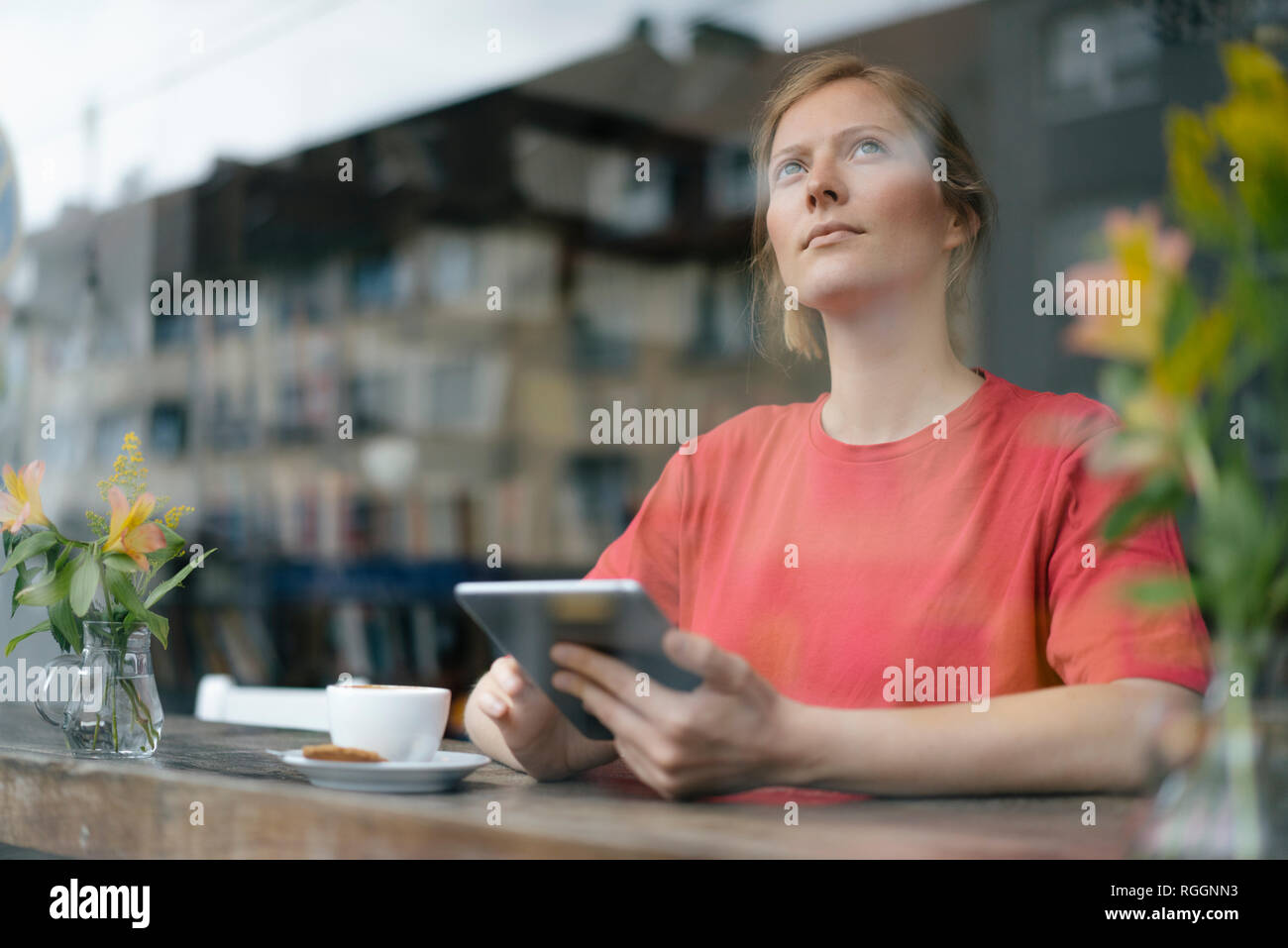 Junge Frau mit Tablet am Fenster in einem Cafe Stockfoto