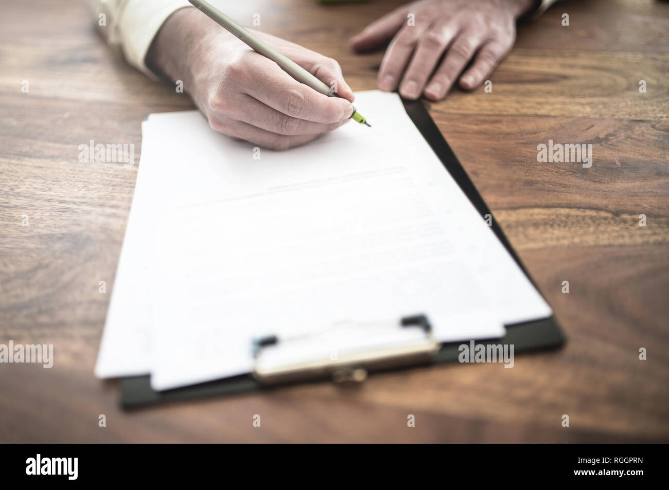 Man unterzeichnen Vertrag an den hölzernen Schreibtisch Stockfoto