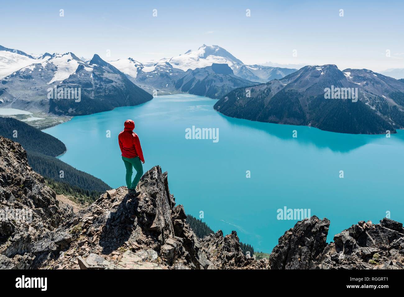 Blick vom Panorama Ridge Wanderweg, Wanderer auf einem Felsen, Garibaldi Lake, Guard Berg und Täuschung Gipfel, Gletscher zurück Stockfoto