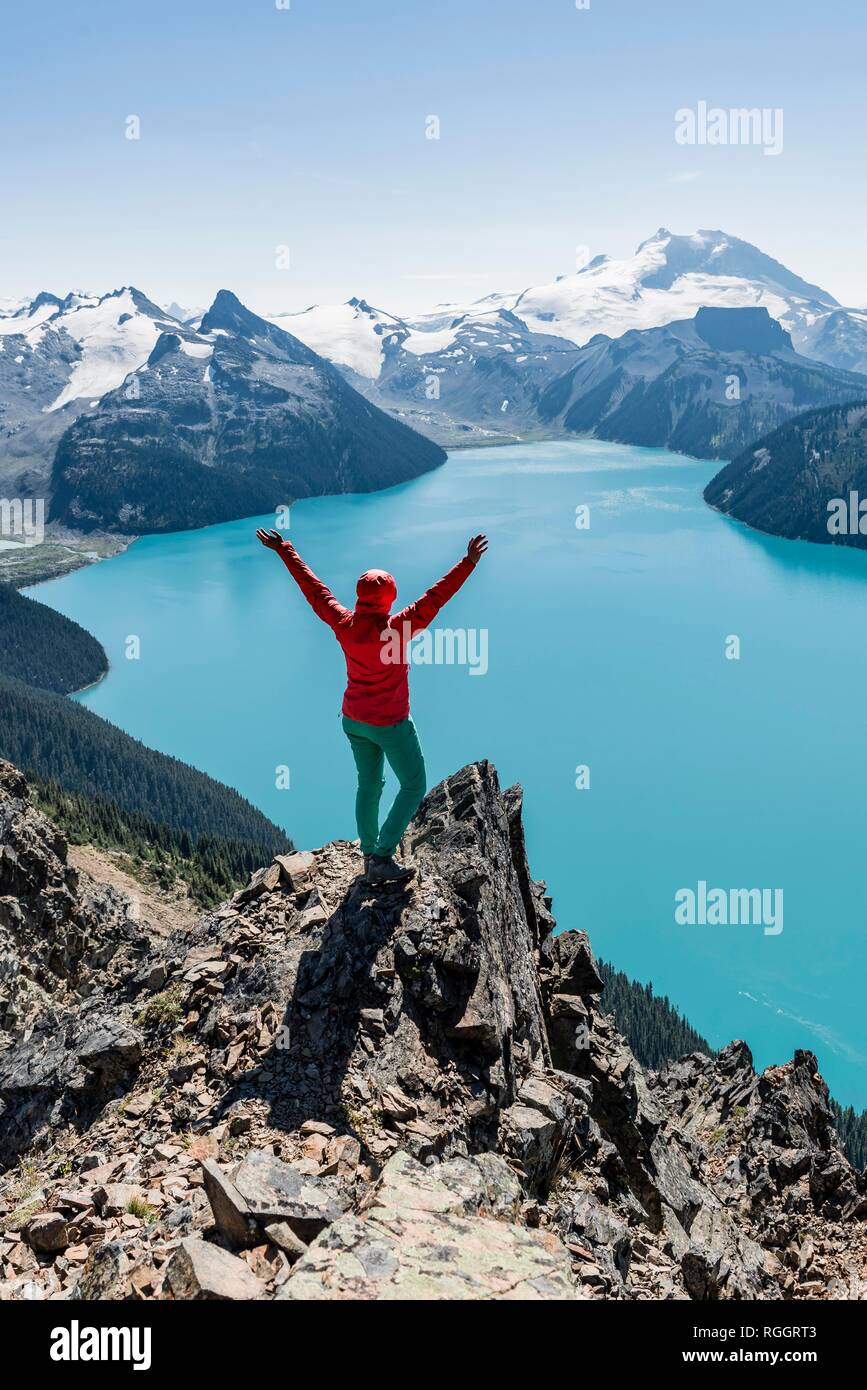 Blick vom Panorama Ridge Wanderweg, Wanderer auf einem Felsen streckt die Arme in die Luft, Garibaldi Lake, türkisfarbene Gletschersee, Stockfoto