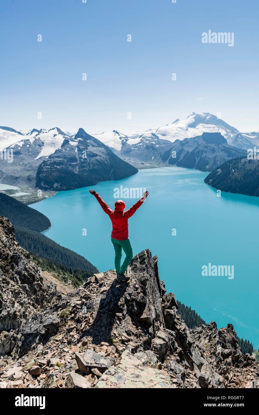Blick vom Panorama Ridge Wanderweg, Wanderer auf einem Felsen streckt die Arme in die Luft, Garibaldi Lake, türkisfarbene Gletschersee, Stockfoto