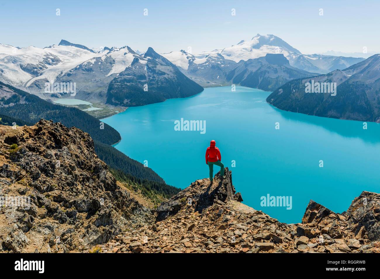 Blick vom Panorama Ridge Wanderweg, Wanderer auf einem Felsen, Garibaldi Lake, Guard Berg und Täuschung Gipfel, Gletscher zurück Stockfoto
