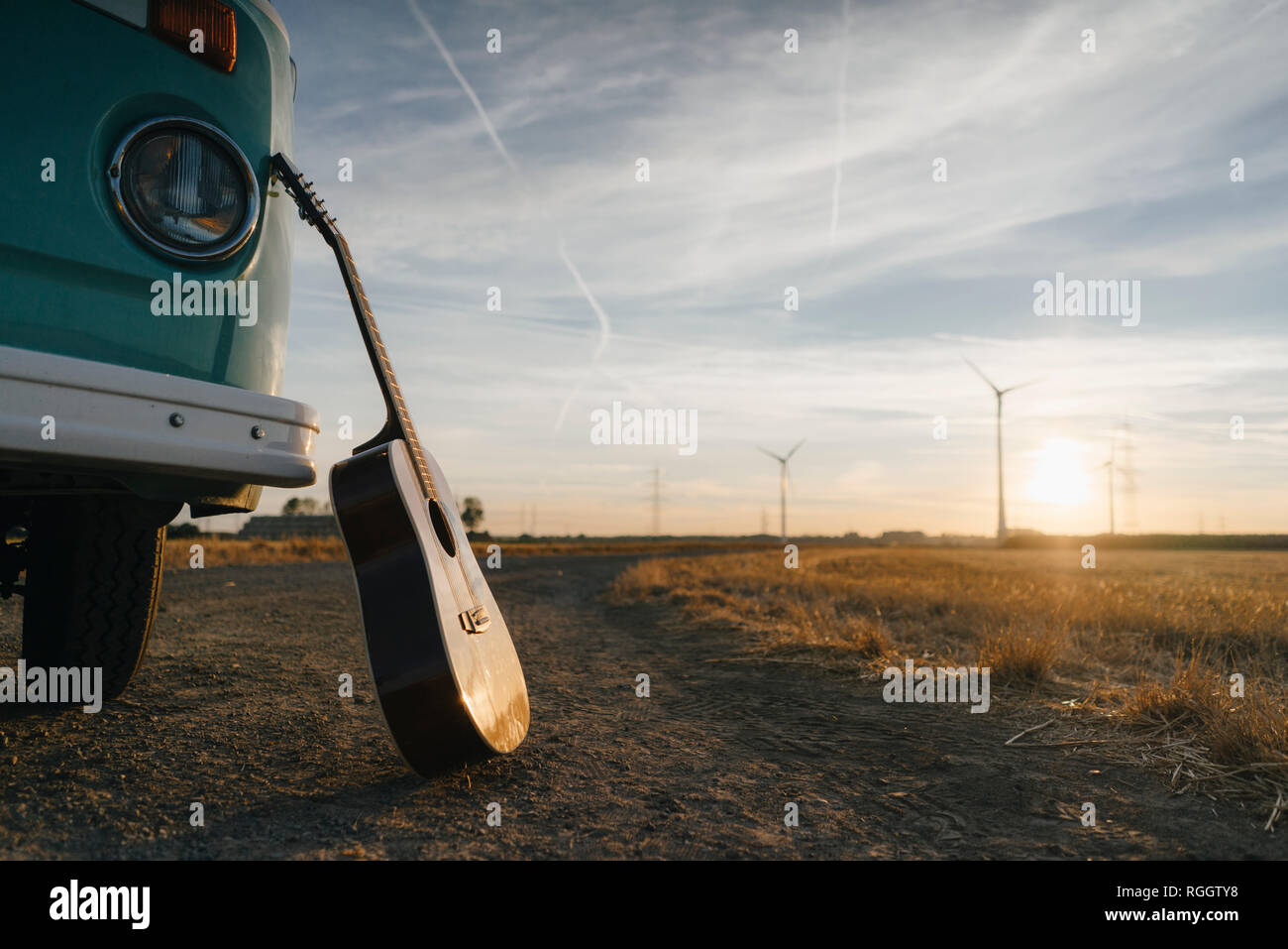 Gitarre gegen Wohnmobil in ländlichen Landschaft schiefen mit Windräder im Sonnenuntergang Stockfoto