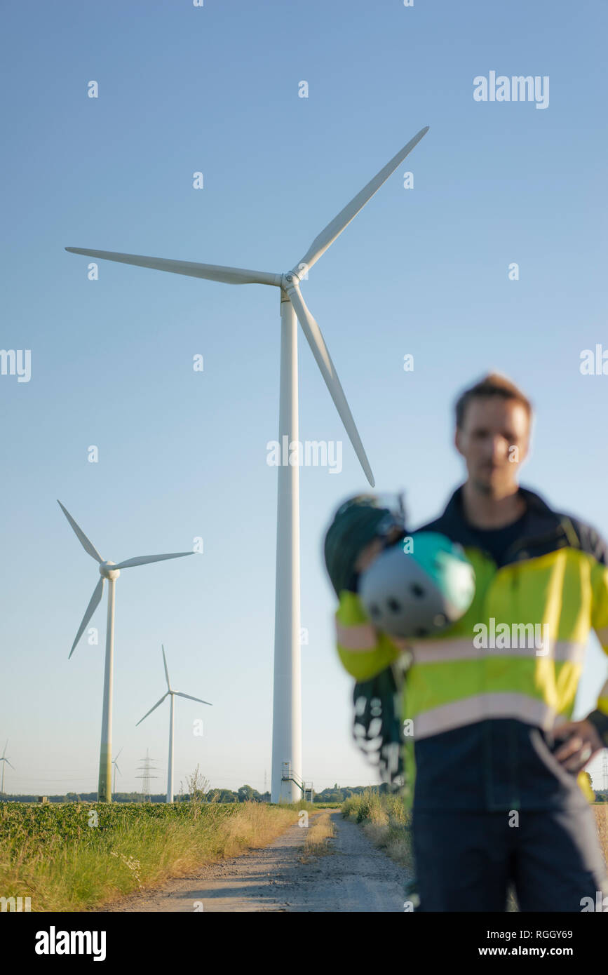 Verschwommene Sicht der Techniker stehen auf Feld Pfad in einen Windpark mit Kletterausrüstung Stockfoto