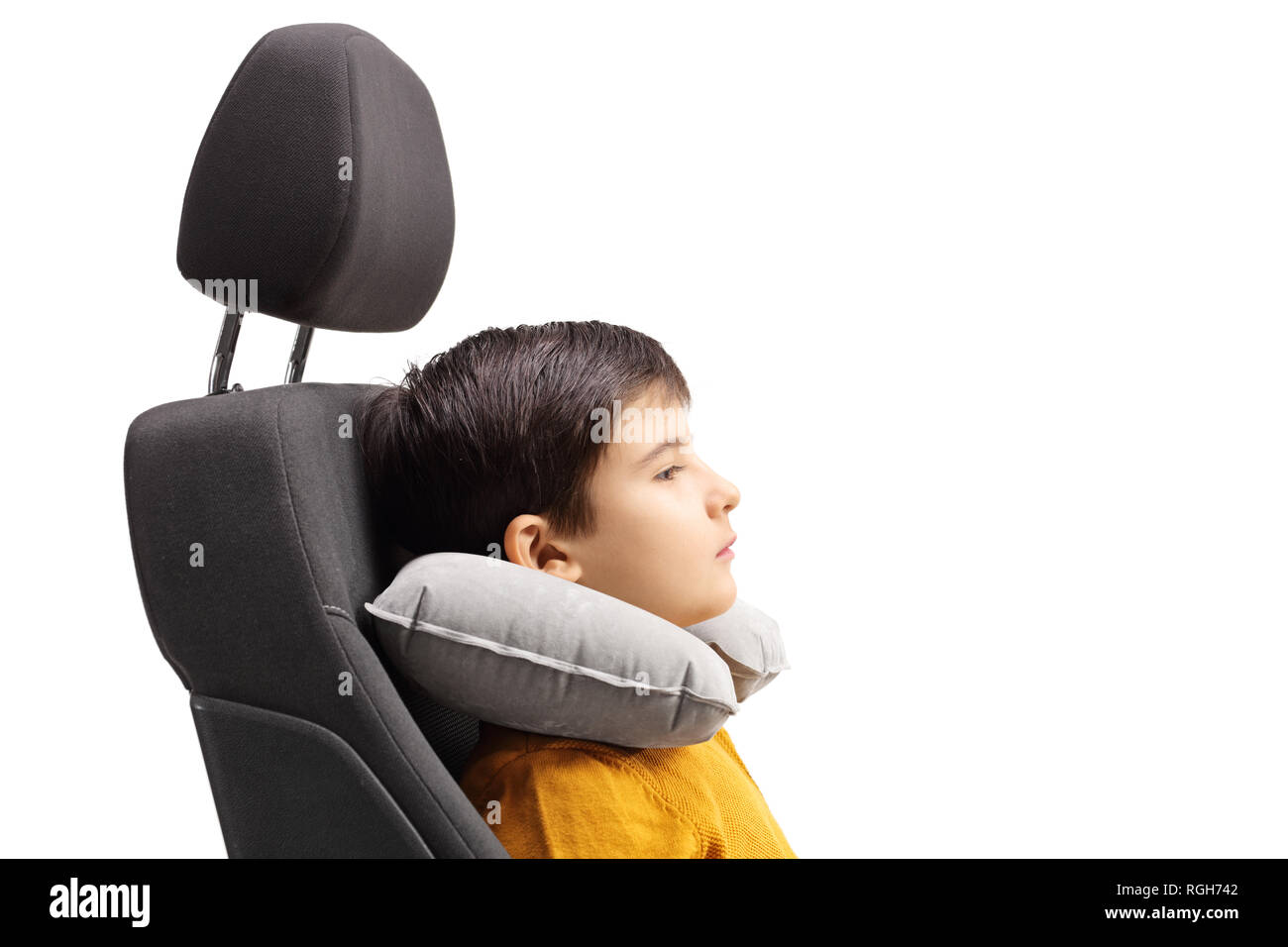 Junge in einem Auto Sitz mit einer Reise Kissen um seinen Hals isoliert auf weißem Hintergrund Stockfoto