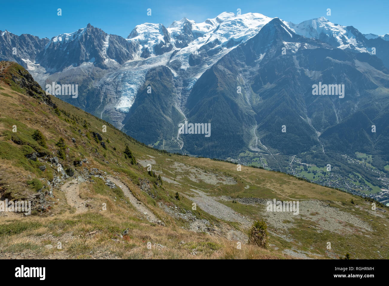 Wanderweg schlängelt sich an steilen Berg über der Stadt Les Houches mit fabelhafter Aussicht auf die Gipfel und Gletscher des Mont Blanc auf einer sonnigen Septemb Stockfoto