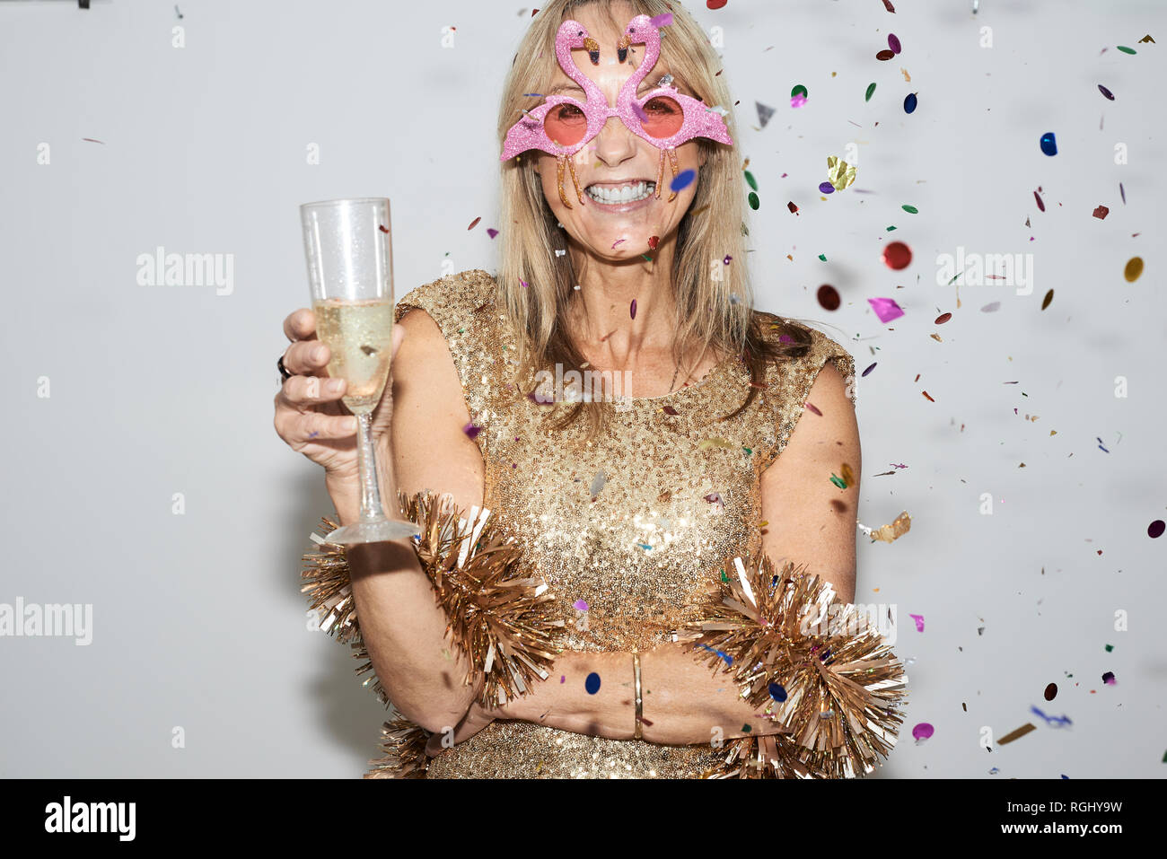 Ältere Frau mit goldenen Kleid und flmingo geformte Gläser, celebtraing Silvester Stockfoto