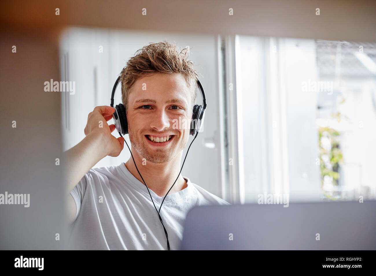 Portrait von lächelnden jungen Mann zu Hause Musik hören mit Kopfhörern Stockfoto