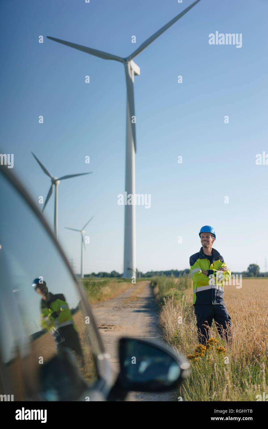 Lächelnd Ingenieur steht ein Feld an einem Windpark Stockfoto